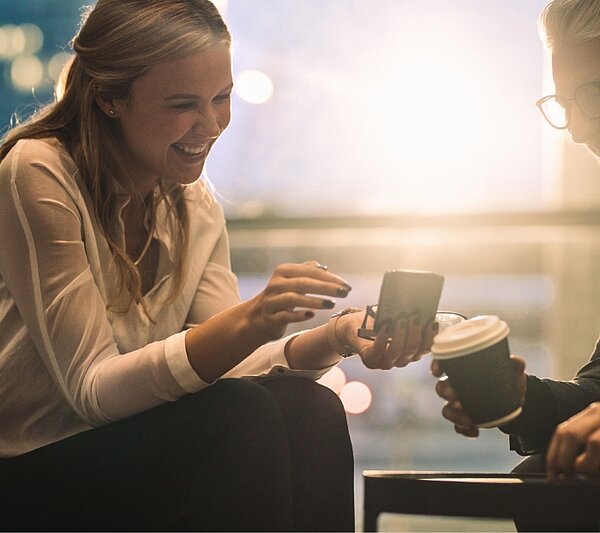 Deux invités savourent le café, vérifient le téléphone pour s'inscrire à des offres exclusives